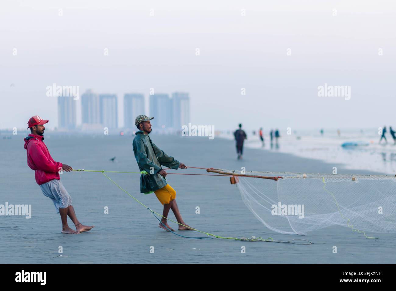 karachi pakistan 2021, a fisherman pulling fishing net to catch fish, at sea view in evening time. Stock Photo