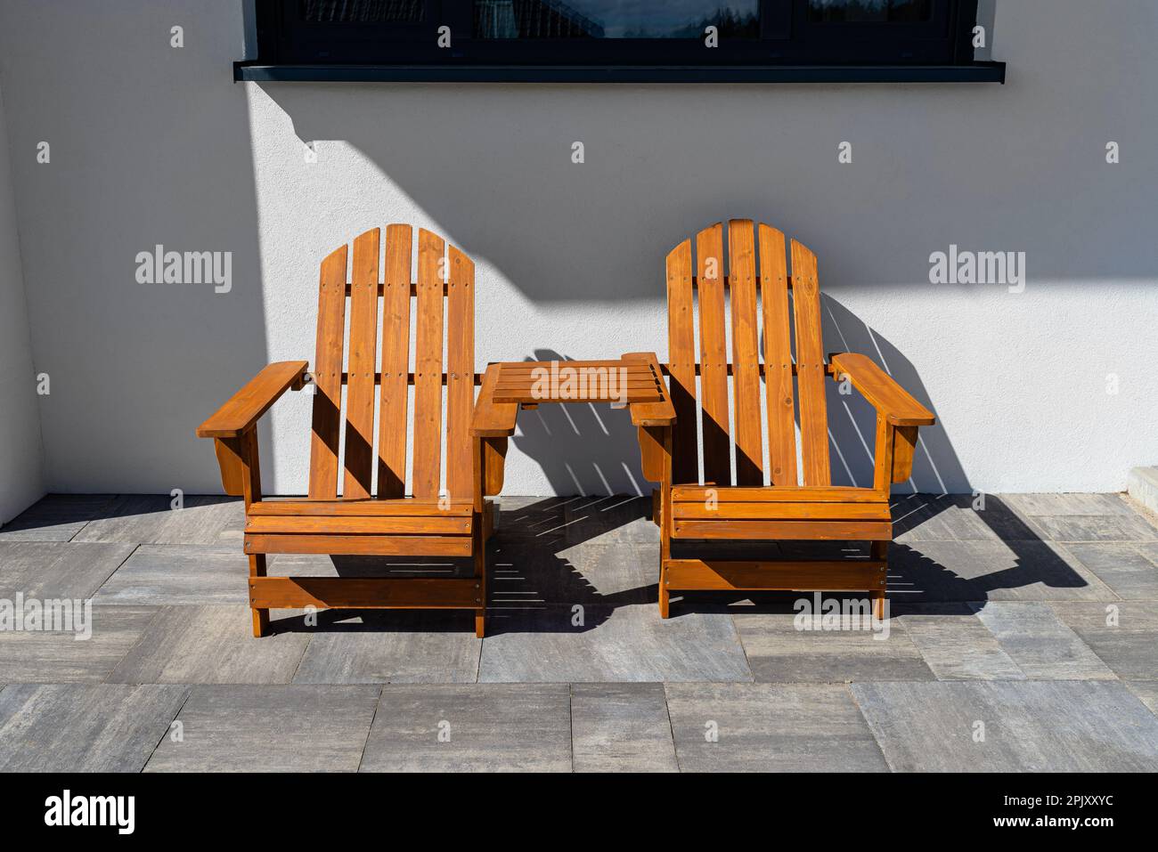 Two wooden chairs connected by a small table standing in front of a
