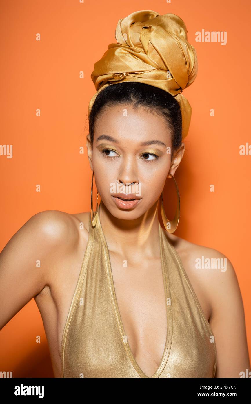 Trendy african american model in headscarf and swimsuit standing on orange background Stock Photo
