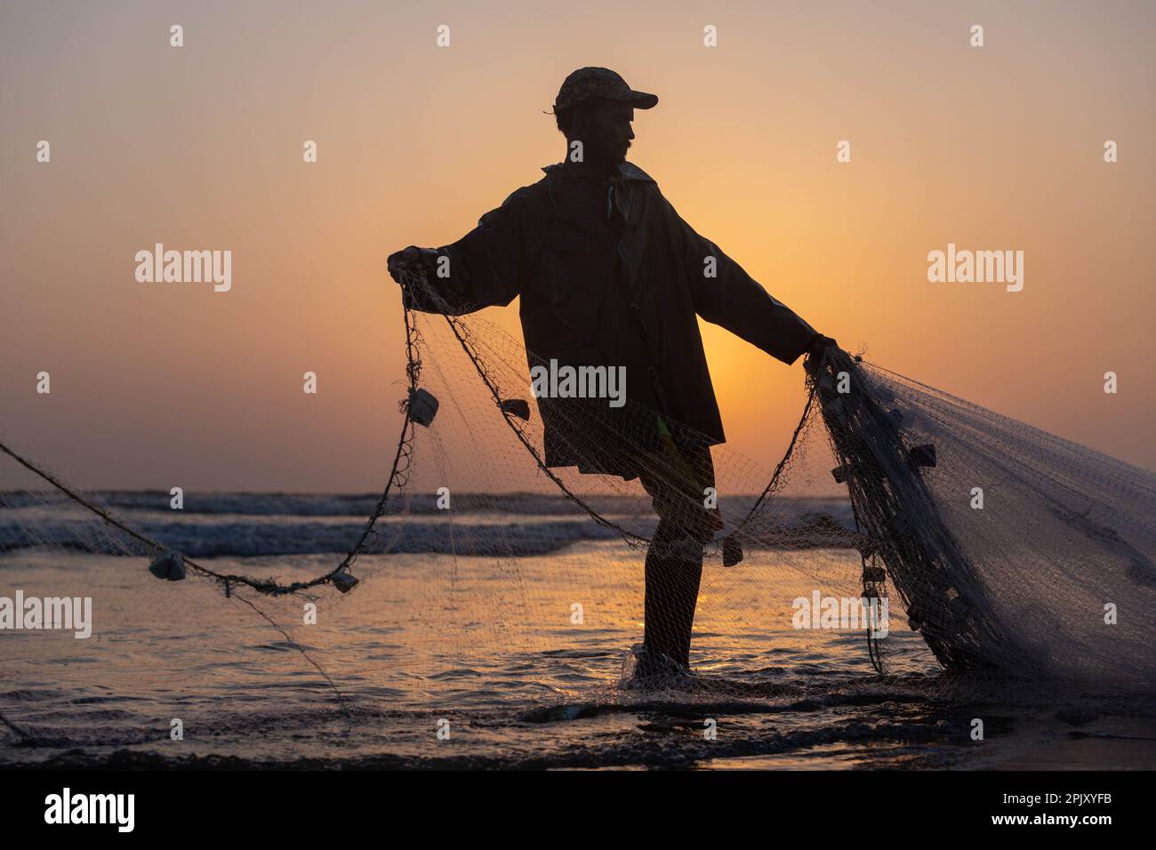 karachi pakistan 2021, a fisherman pulling fishing net to catch fish, at sea view in evening