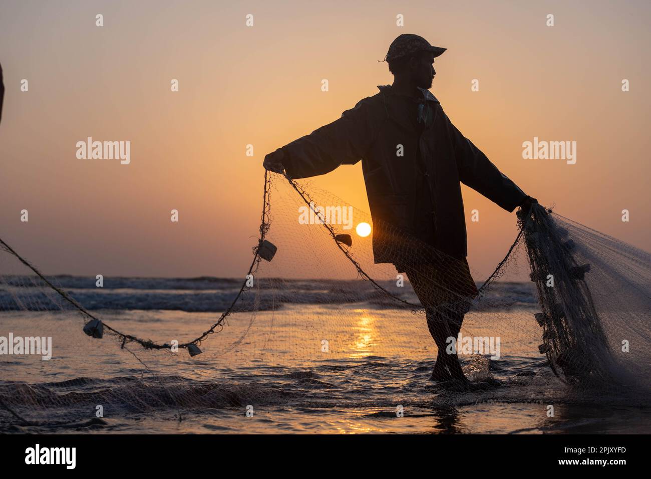 karachi pakistan 2021, a fisherman pulling fishing net to catch fish, at  sea view in evening time Stock Photo - Alamy