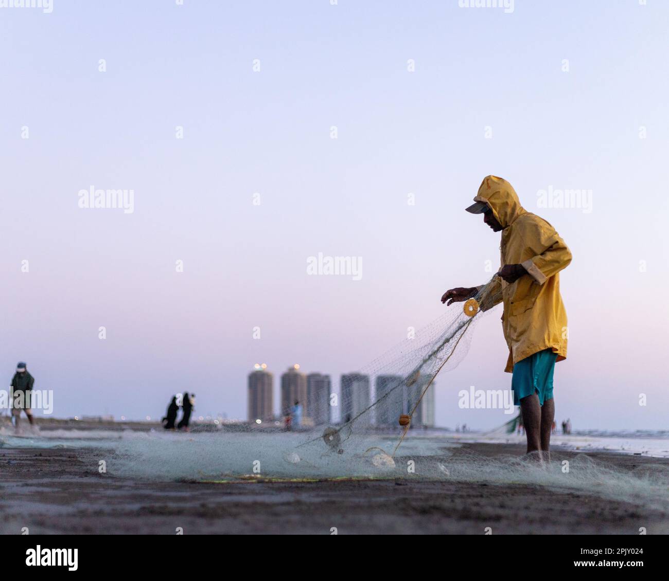 karachi pakistan 2021, a fisherman wearing yellow jacket preparing