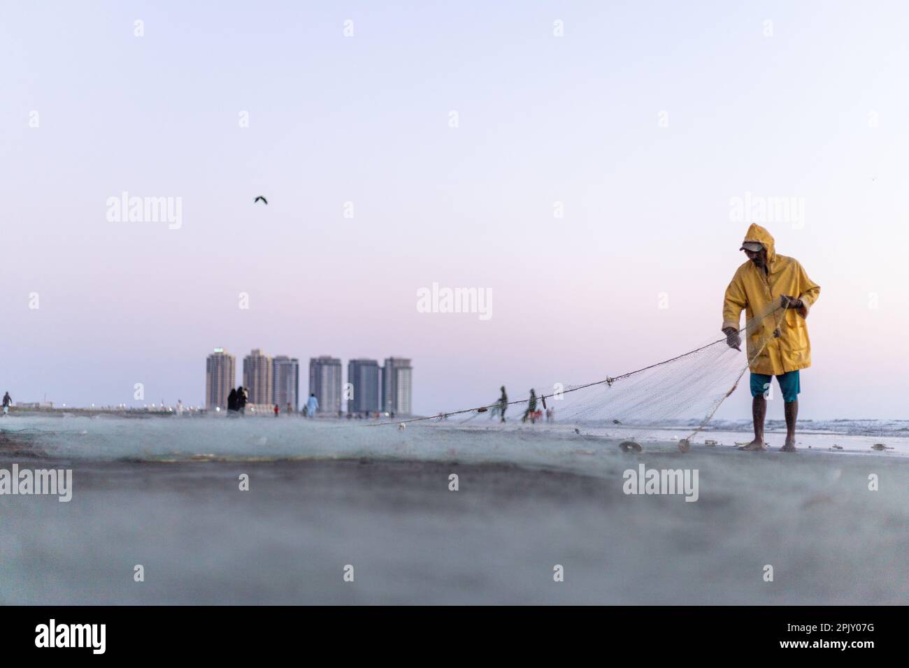 karachi pakistan 2021, a fisherman wearing yellow jacket preparing