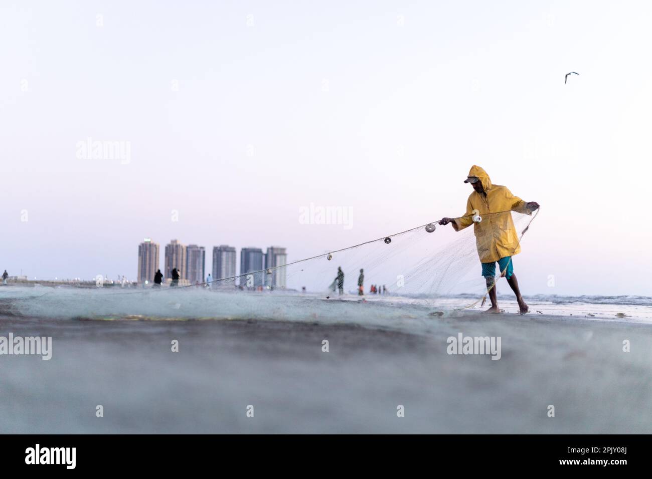 karachi pakistan 2021, a fisherman wearing yellow jacket preparing