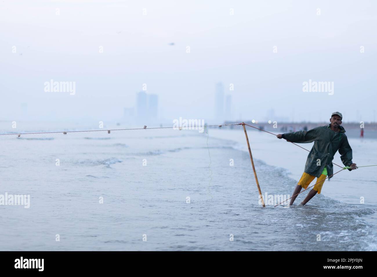 karachi pakistan 2021, a fisherman pulling fishing net to catch fish, at sea view in evening