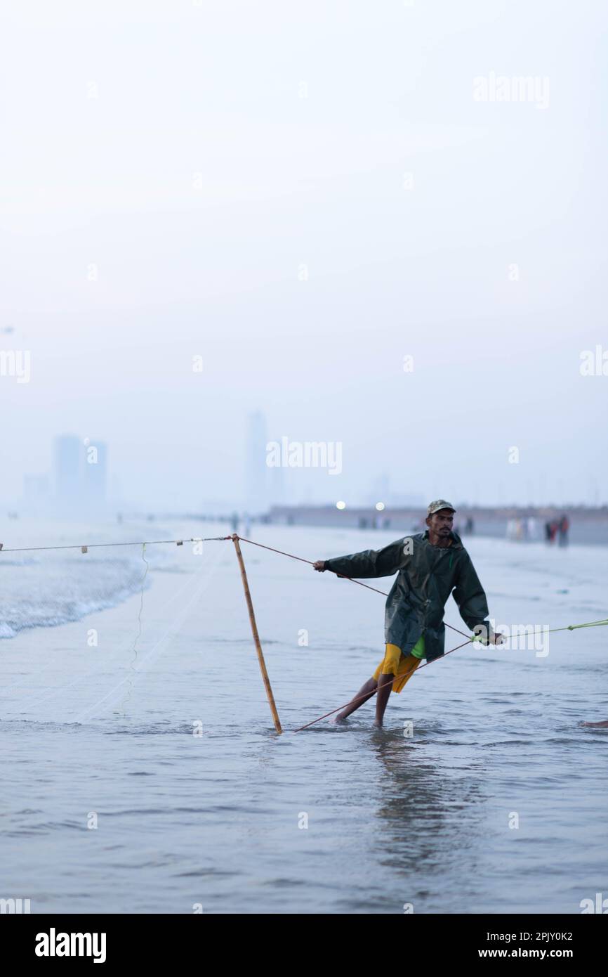 karachi pakistan 2021, a fisherman pulling fishing net to catch fish, at sea view in evening time. Stock Photo