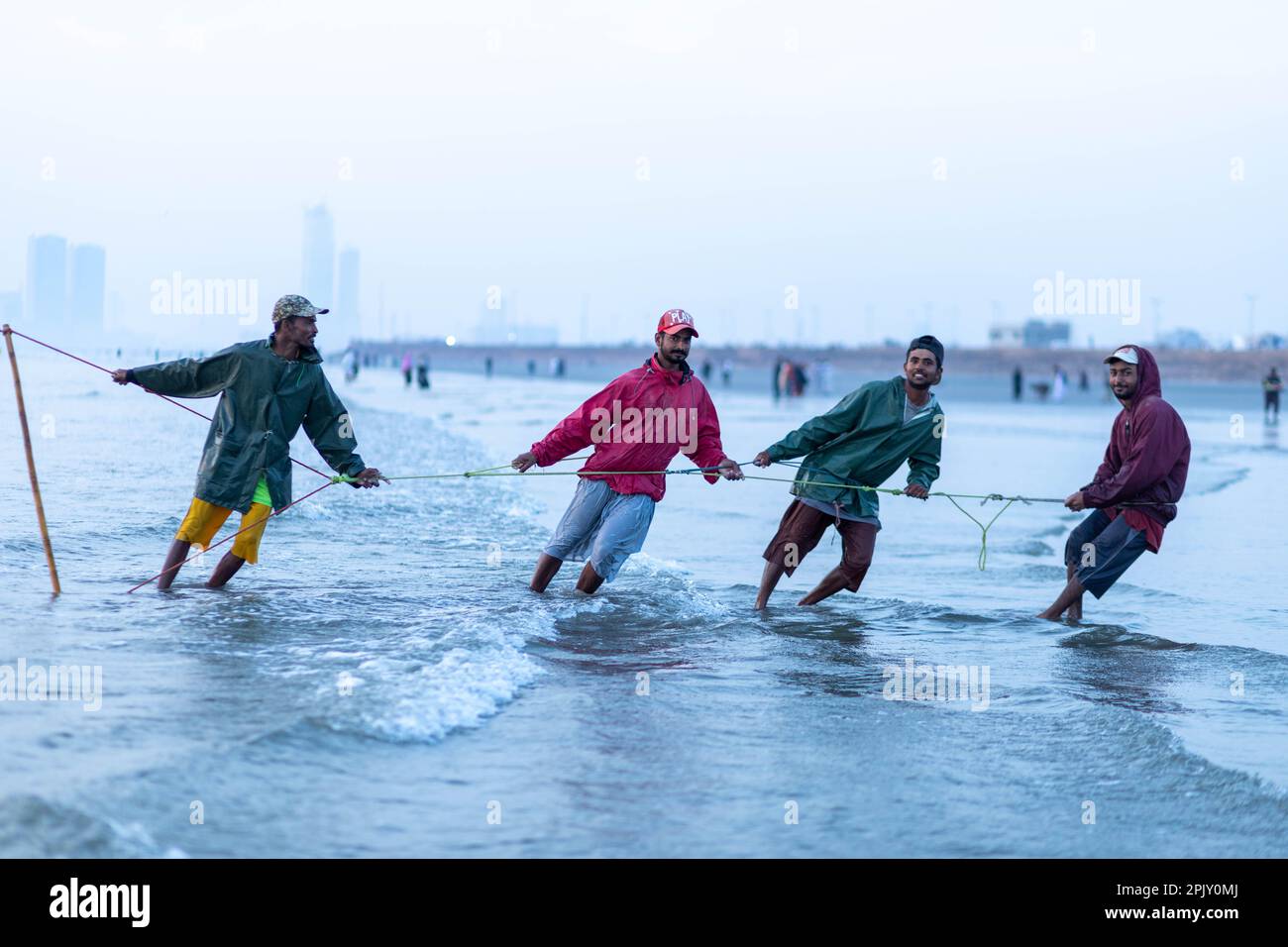karachi pakistan 2021, a fisherman pulling fishing net to catch fish, at sea view in evening