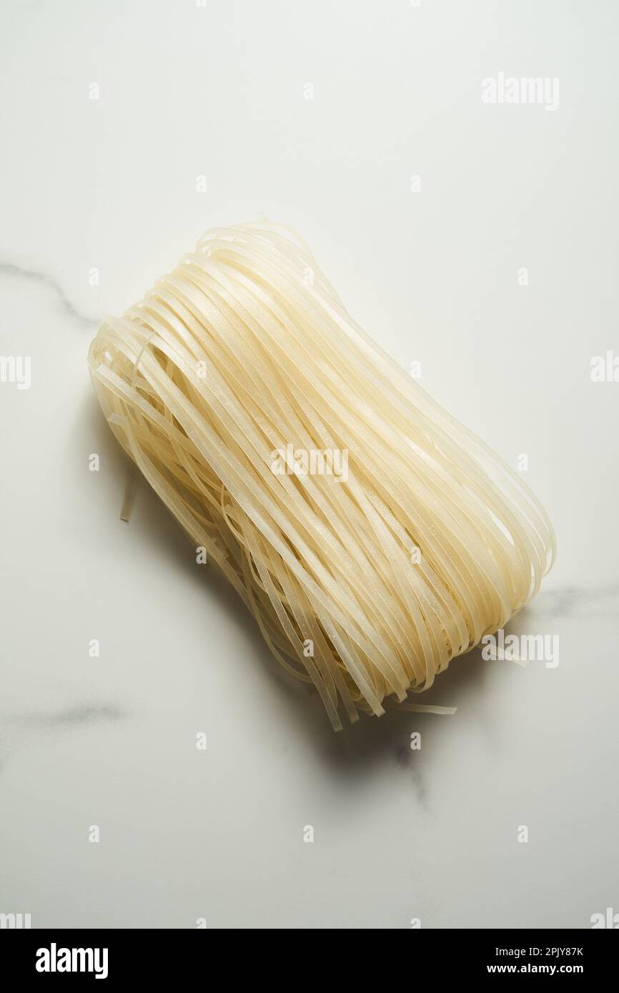 Wide rice noodle on white and clean marble background. Raw and uncooked
