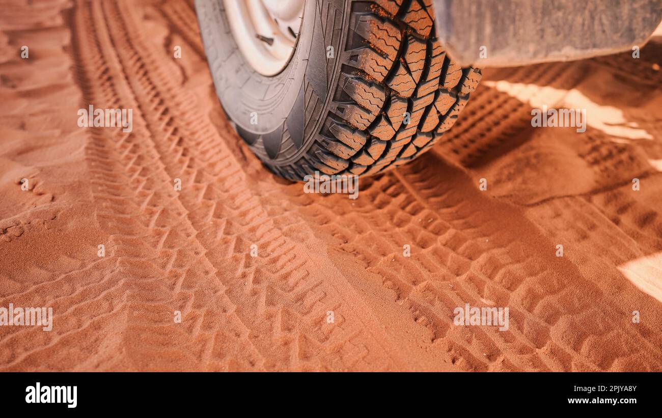 4wd vehicle tyre, dirty from dust - track print visible in red sand ...
