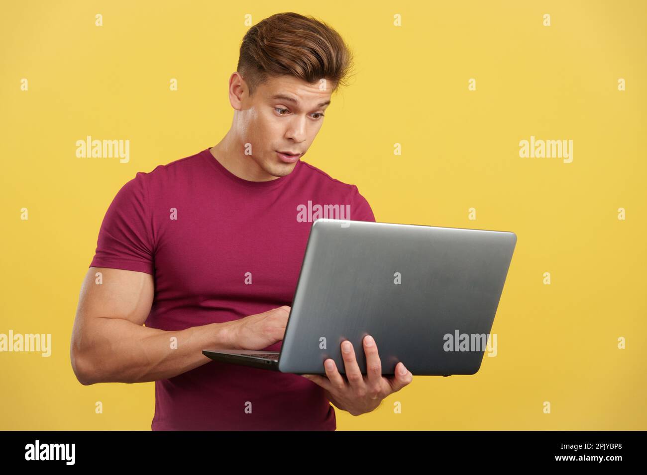 Surprised strong man standing using a laptop Stock Photo