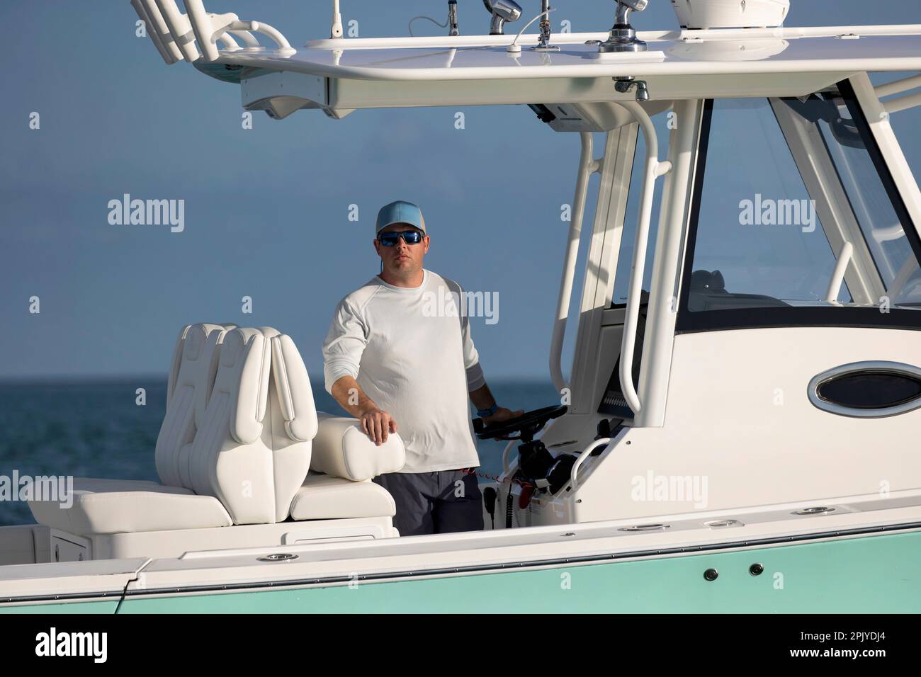 A man standing at the helm of a center console boat Stock Photo Alamy