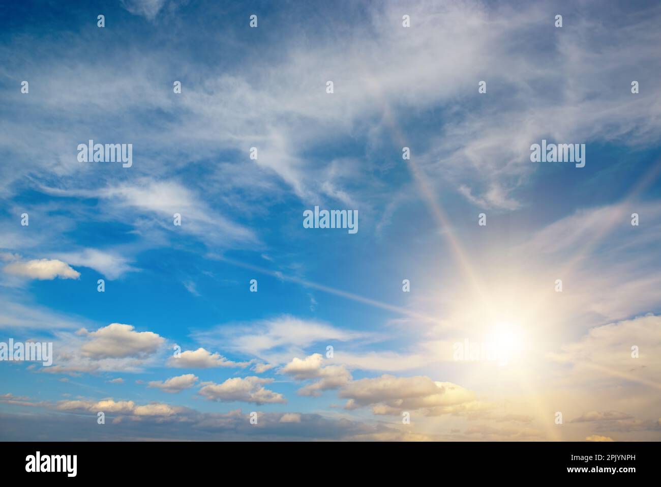 Bright sun on beautiful blue sky with white fluffy clouds. Stock Photo