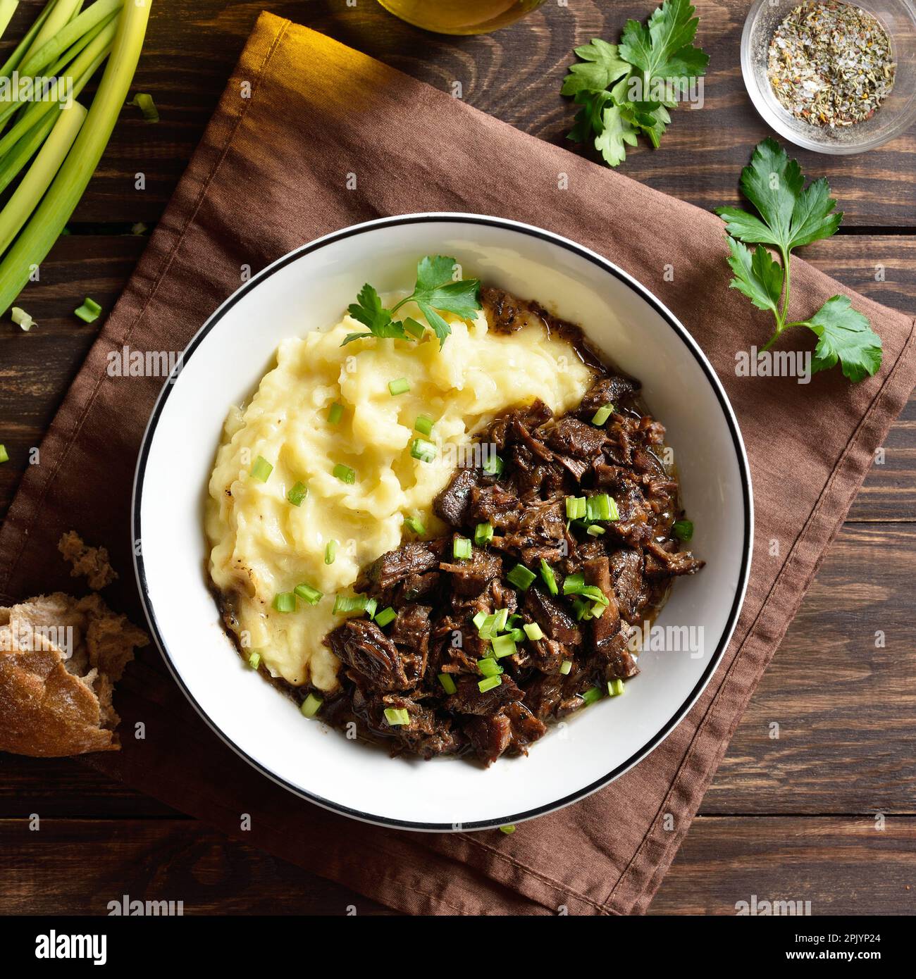 Slow cooked beef with mashed potatoes in bowl over wooden table. Top