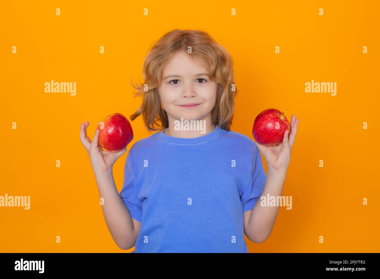 Kids face with fruits. Kid with apple in studio. Studio portrait of cute child hold apple isolated on yellow background Stock Photo