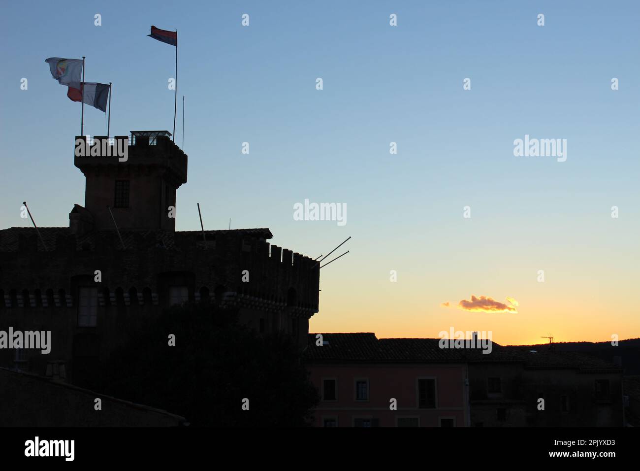 Silhouette of Château Grimaldi in Haut de Cagnes at sunset with flags flying high in the wind (Cagnes sur Mer, France). Medieval castle at twilight Stock Photo