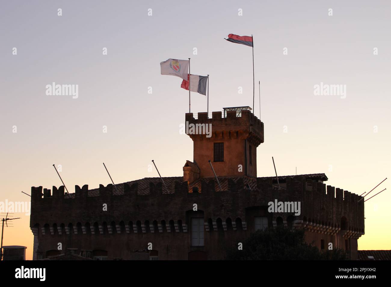 Top of Château Grimaldi in Haut de Cagnes at twilight with flags flying high in the wind (Cagnes sur Mer, France). Medieval castle at twilight Stock Photo