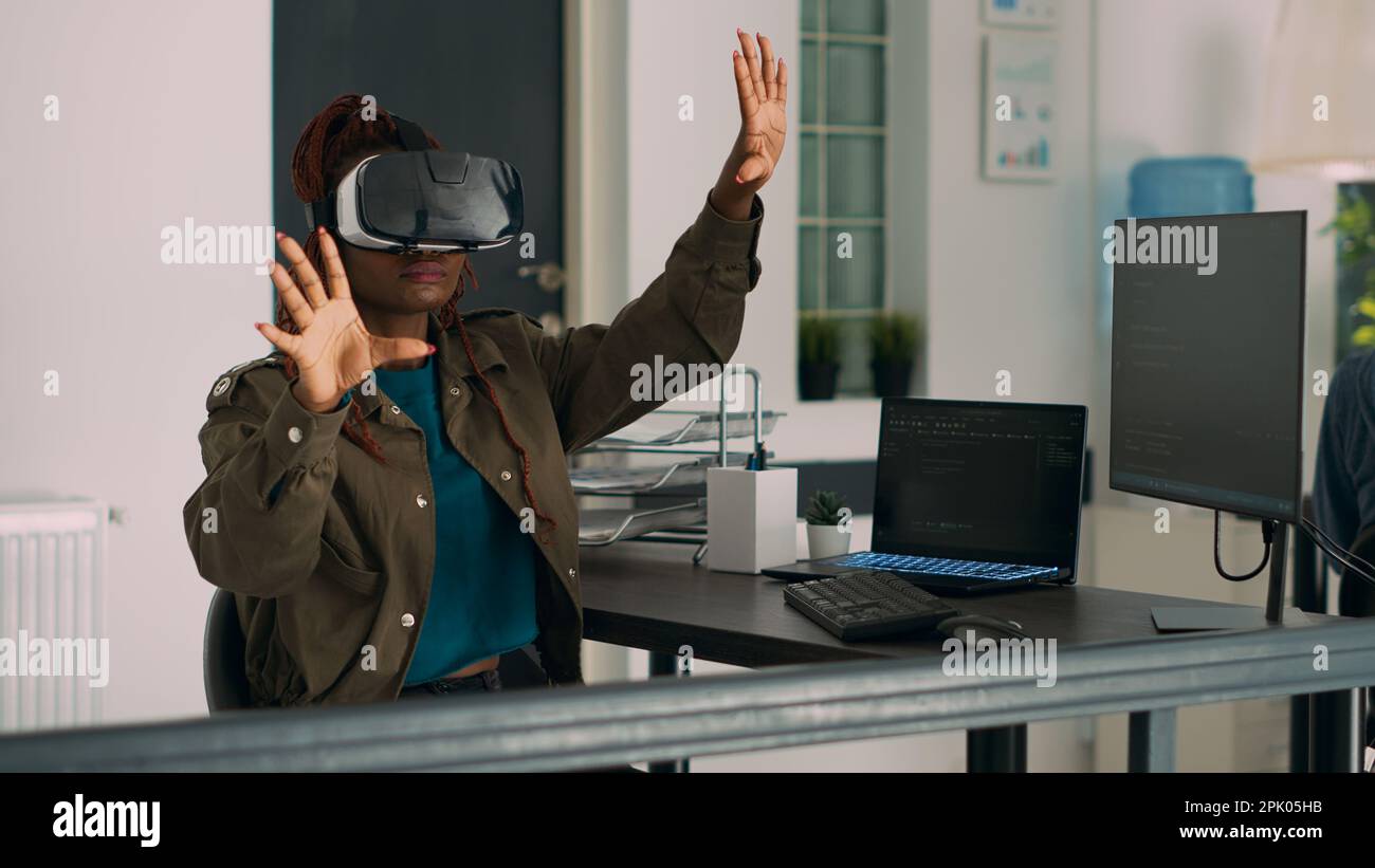 African american developer working with vr glasses to create programming server with html script on terminal window. System engineer using virtual reality headset to plan new interface. Stock Photo