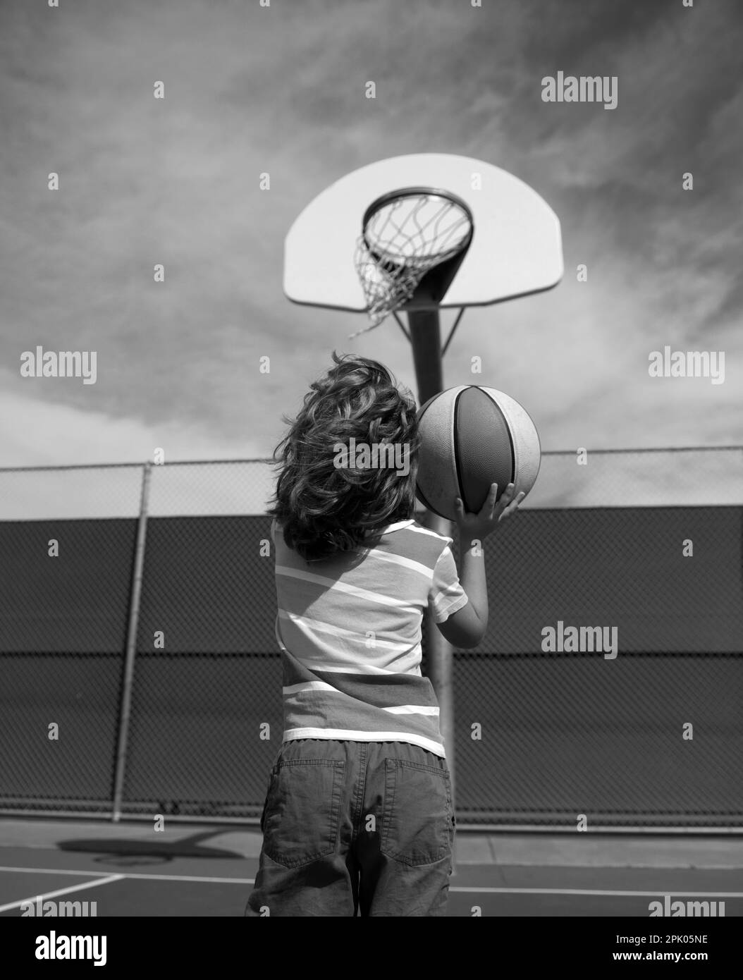 Cute smiling boy plays basketball. Active kids enjoying outdoor game