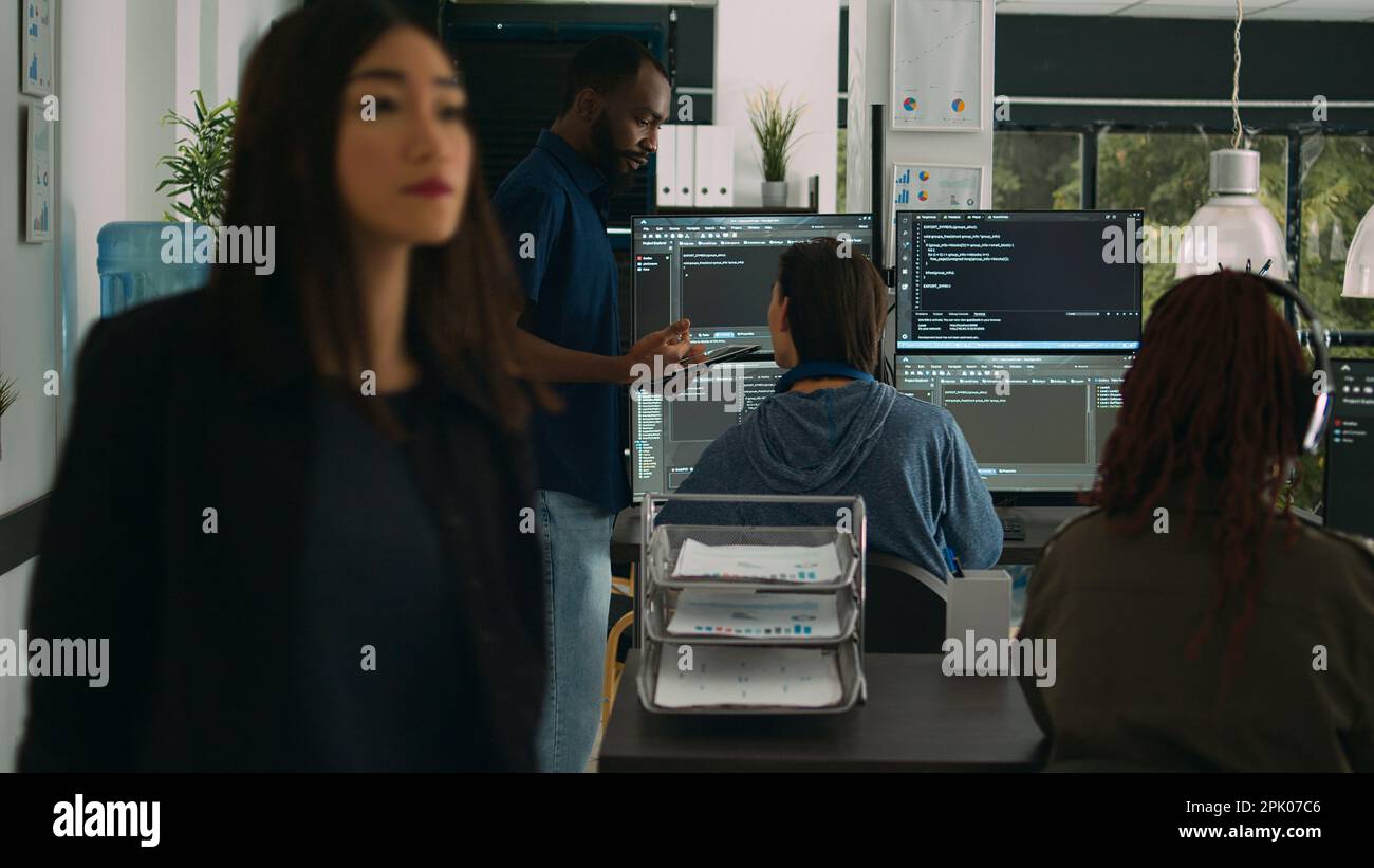 Software programmers talking about algorithms on big screen and tablet, analyzing html script language. Team of system engineers discussing database on terminal window, server interface. Stock Photo