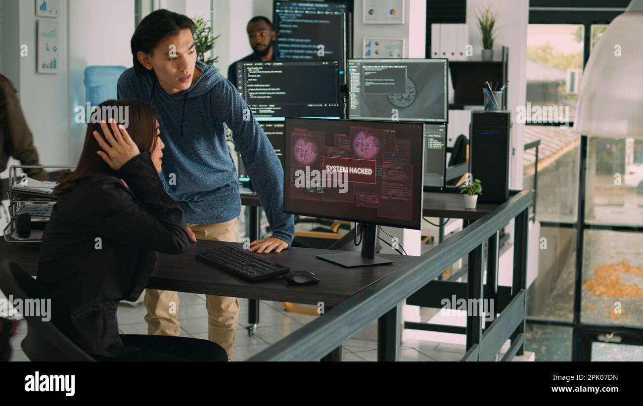 Diverse team of artificial intelligence cloud programers being hacked on firewall server. Web developers looking at critical error on software html script, doing teamwork in agency office. Stock Photo