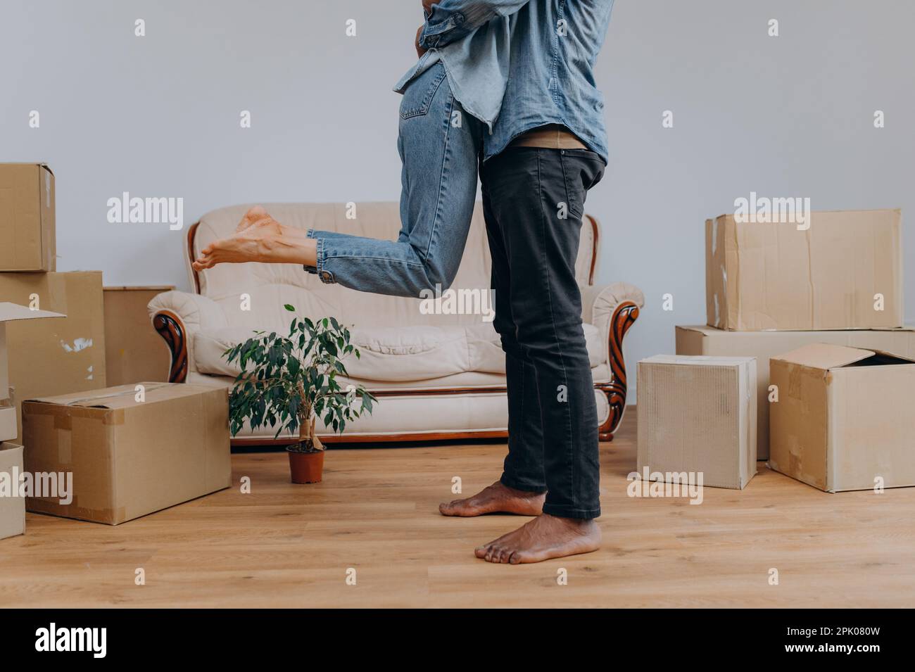 Close up of young man in jeans, wife surrounded by cardboard boxes, happy african american