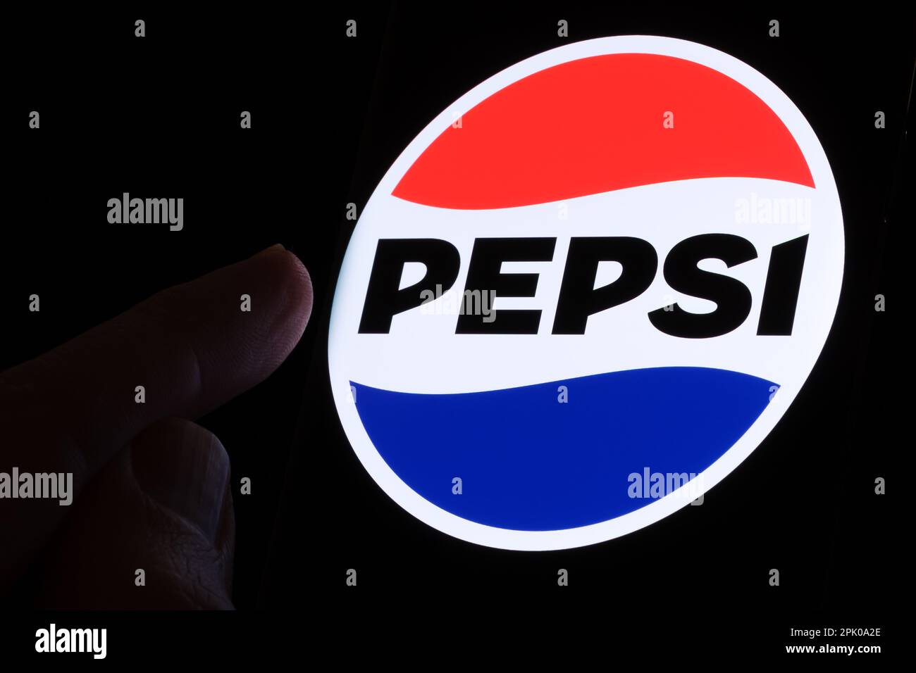 PEPSI new logo introduced in 2023 seen on the screen glowing in the dark and finger is pointing at it. Stafford, United Kingdom, April 3, 2023 Stock Photo
