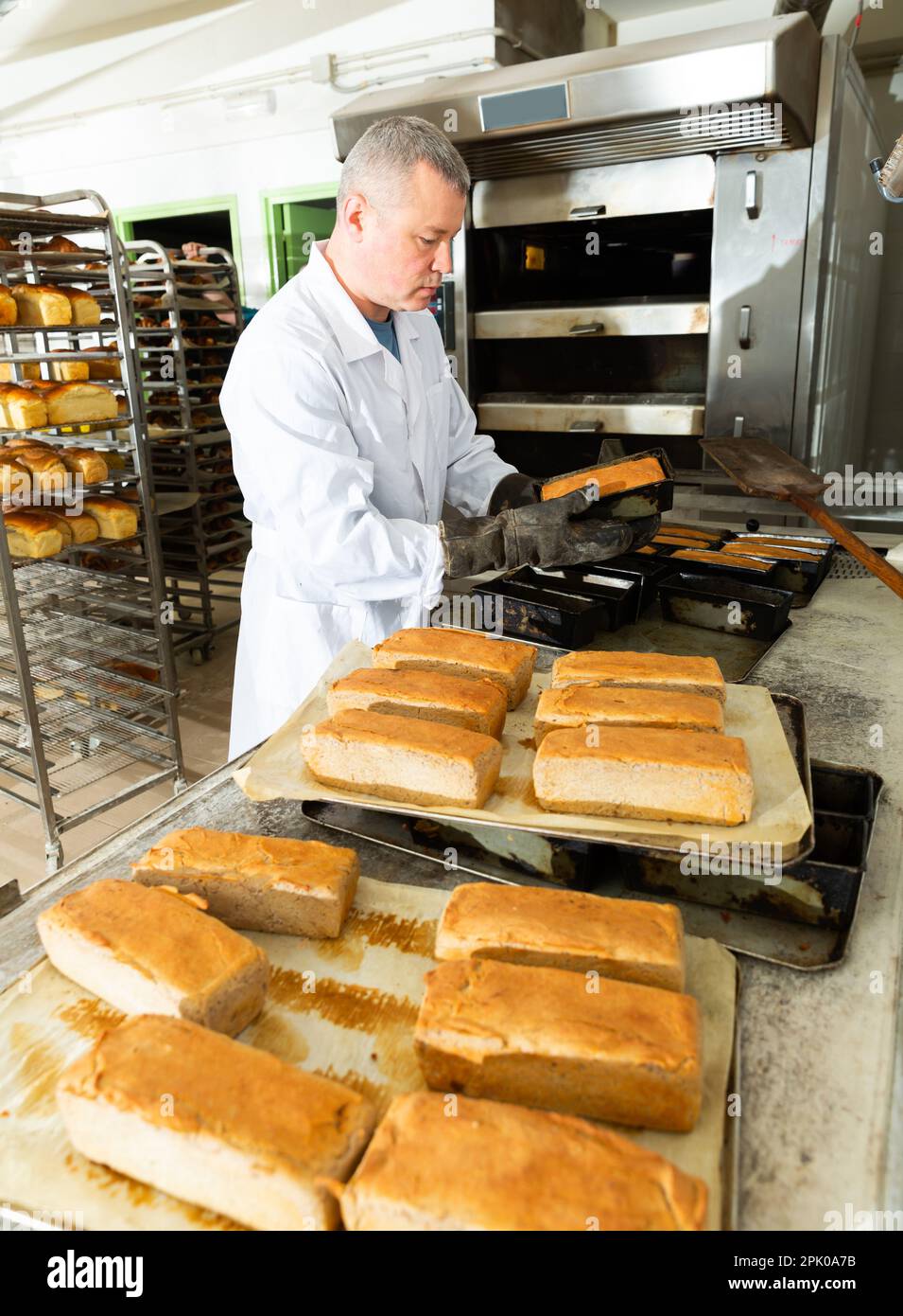 Bake taking out bread from baking pans Stock Photo