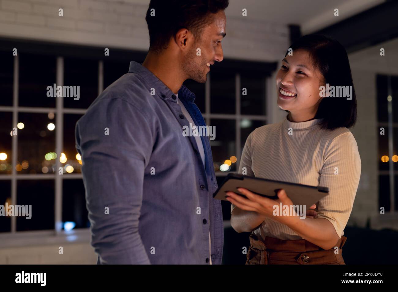 Diverse happy business people using tablet together and discussing, working late at office Stock Photo
