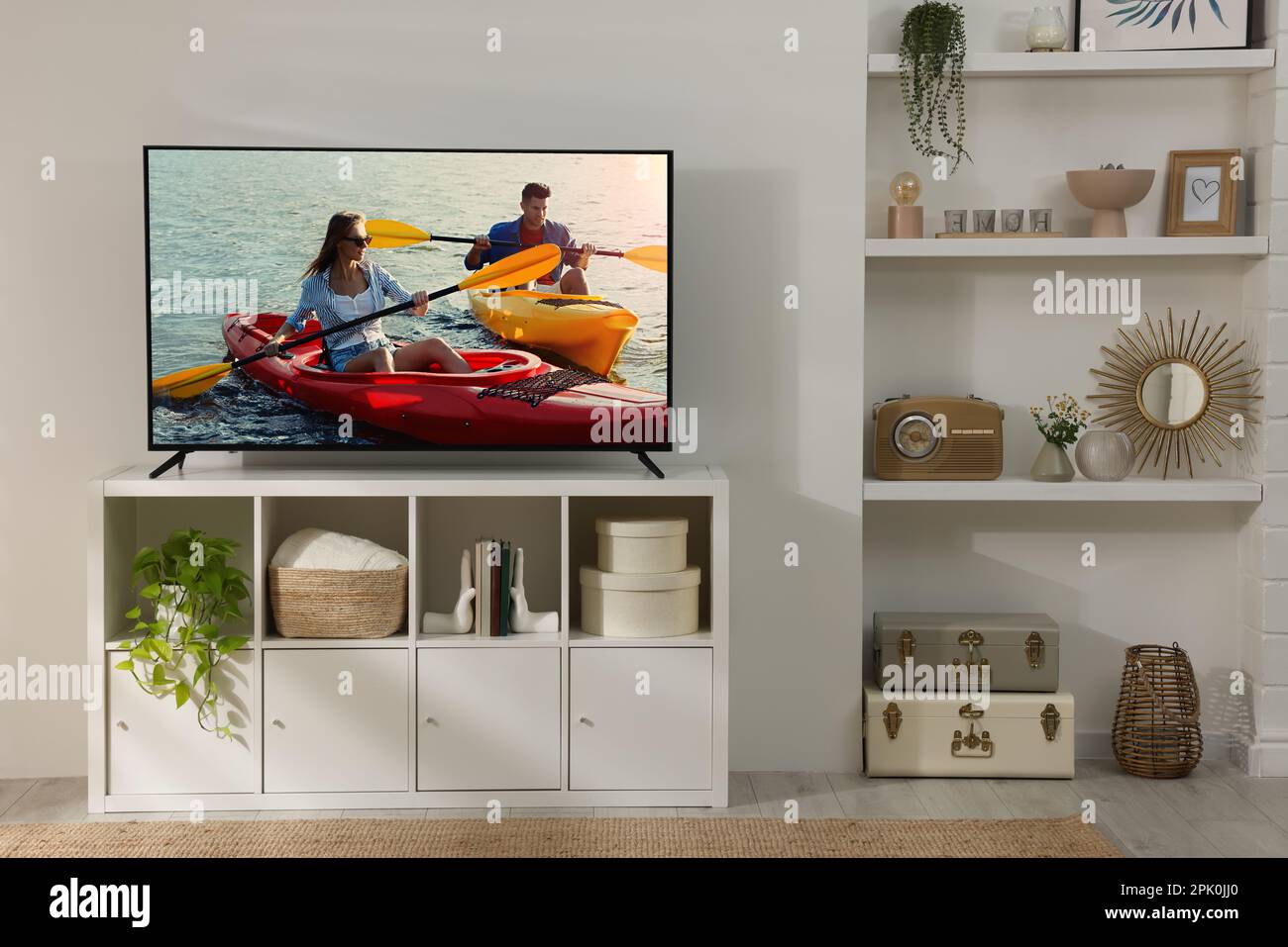 Modern TV set on wooden stand in room. Scene of adventure movie on screen Stock Photo