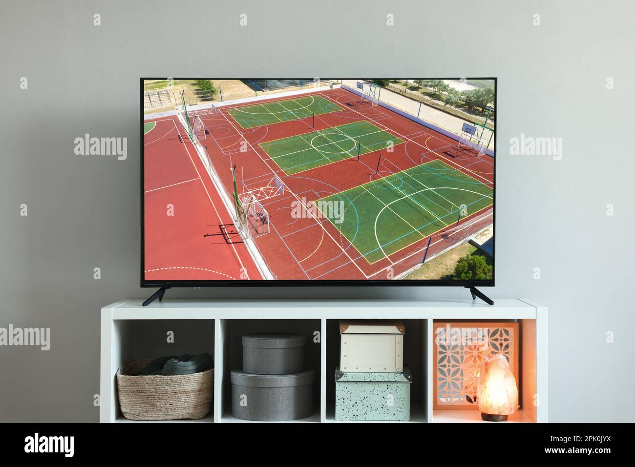 Modern TV set on wooden stand in room. Scene of sport broadcasting Stock Photo