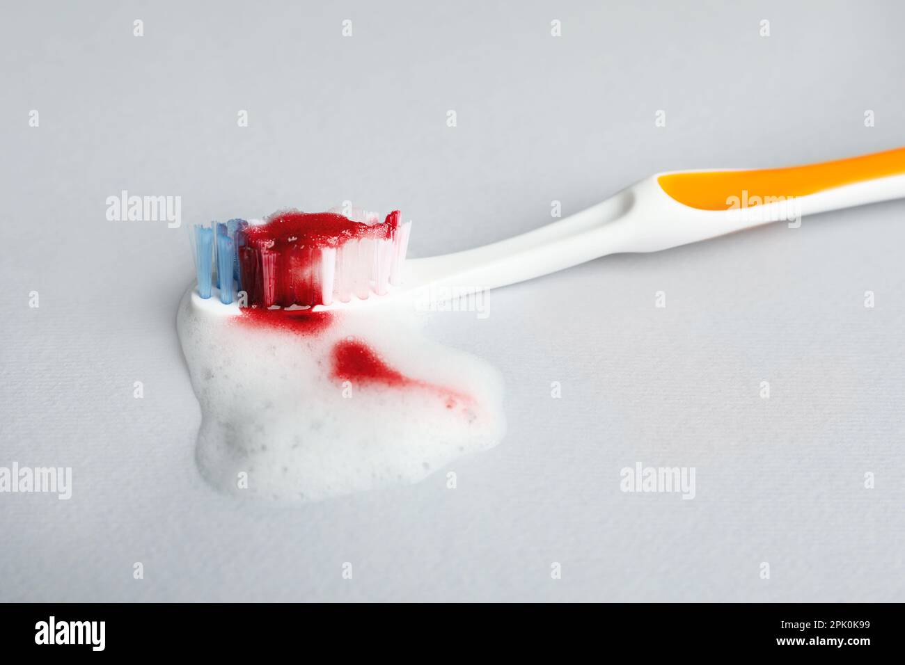 Toothbrush with paste and blood on white background, closeup. Gum