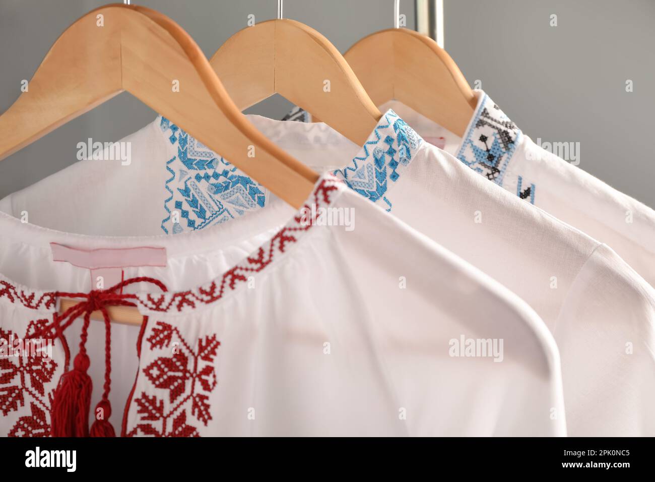 Beautiful shirts with different embroidery designs hanging on grey ...