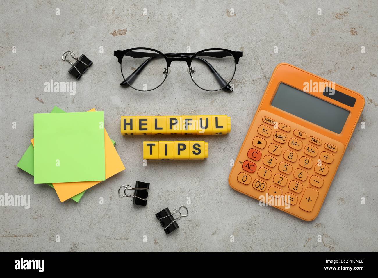 Flat lay composition with text Helpful Tips of yellow cubes on grey table Stock Photo