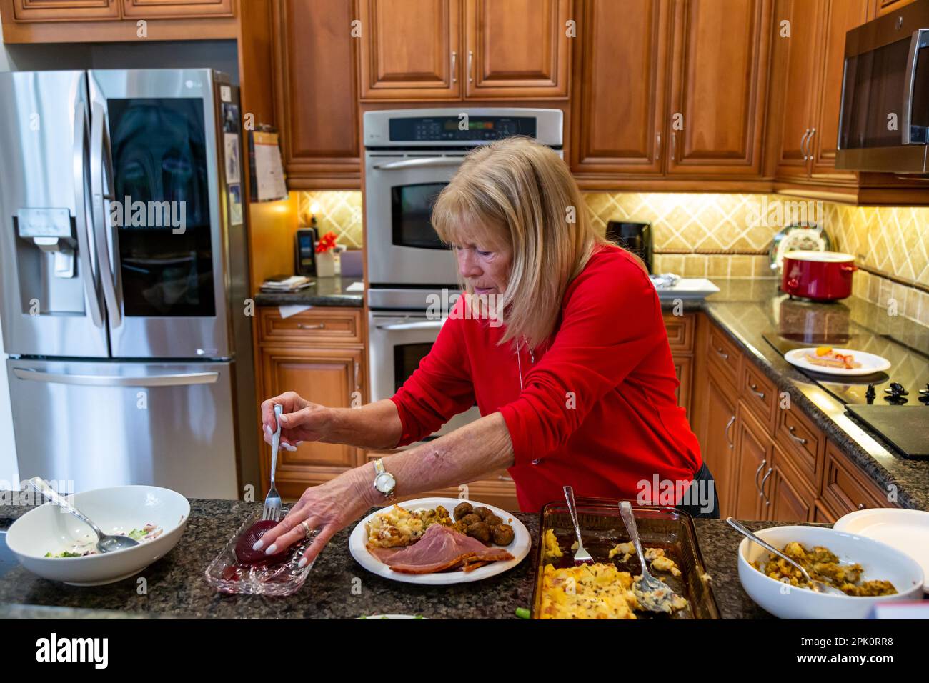 A woman prepares a meal in her American kitchen. Stock Photo