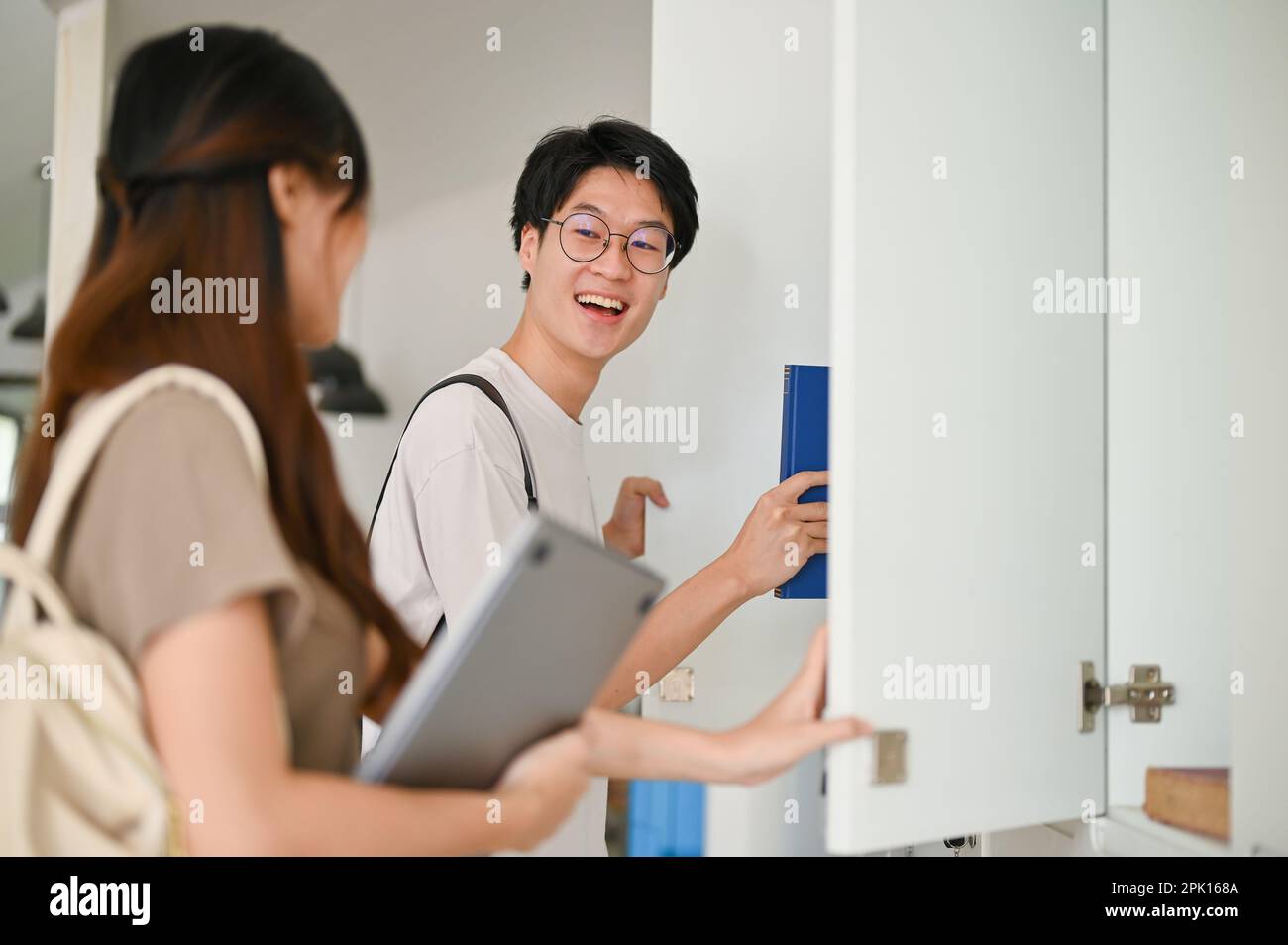 Cheerful and happy young Asian male college student talking with his ...