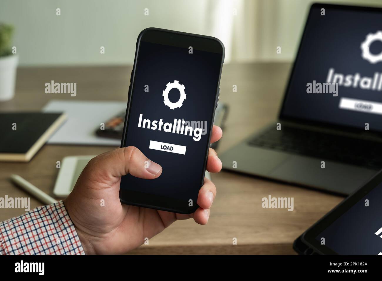 man installing Software Update On Mobile Phone And Laptop digital technology communication Stock Photo