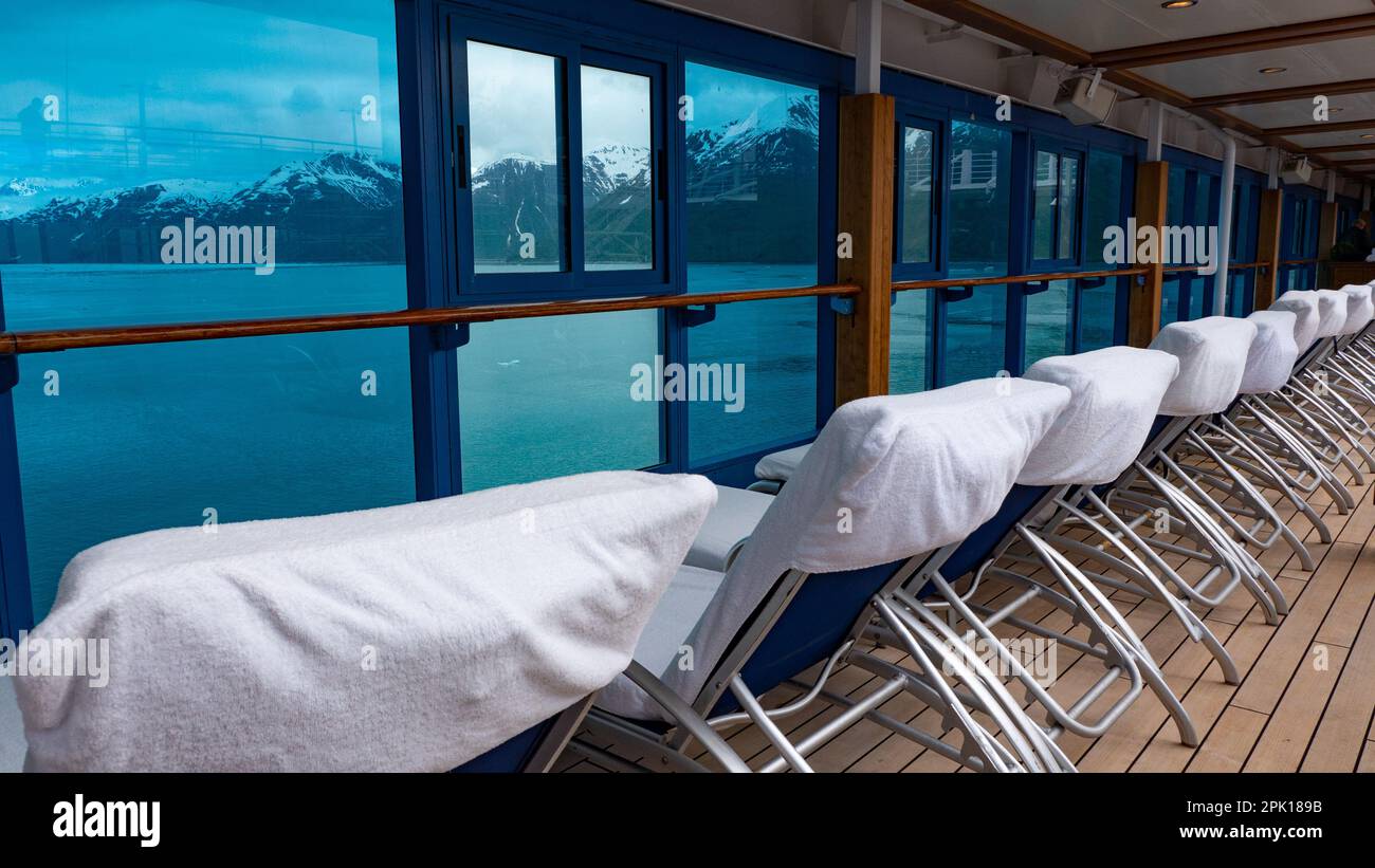 Daybeds in row. Window view to coastal landscape of fjords and glaciers from resort daybeds Stock Photo