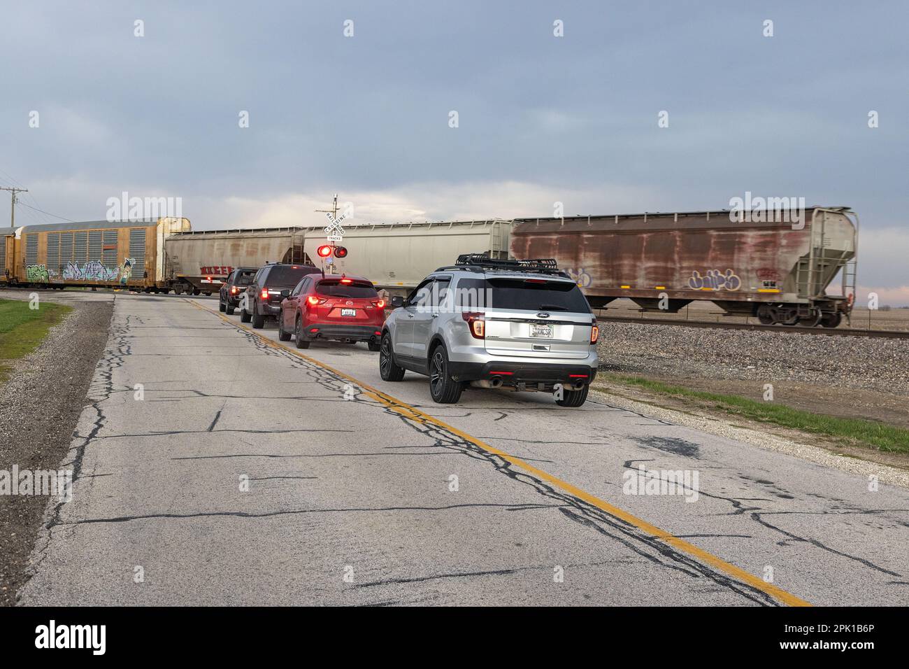 Stronghurst, Illinois, USA. 4th April, 2023. A procession of storm chasers near Stronghurst, Illinois, USA  waiting at a train crossing while driving to a severe storm with tornadic activity several miles away near the city of Macomb. Stock Photo