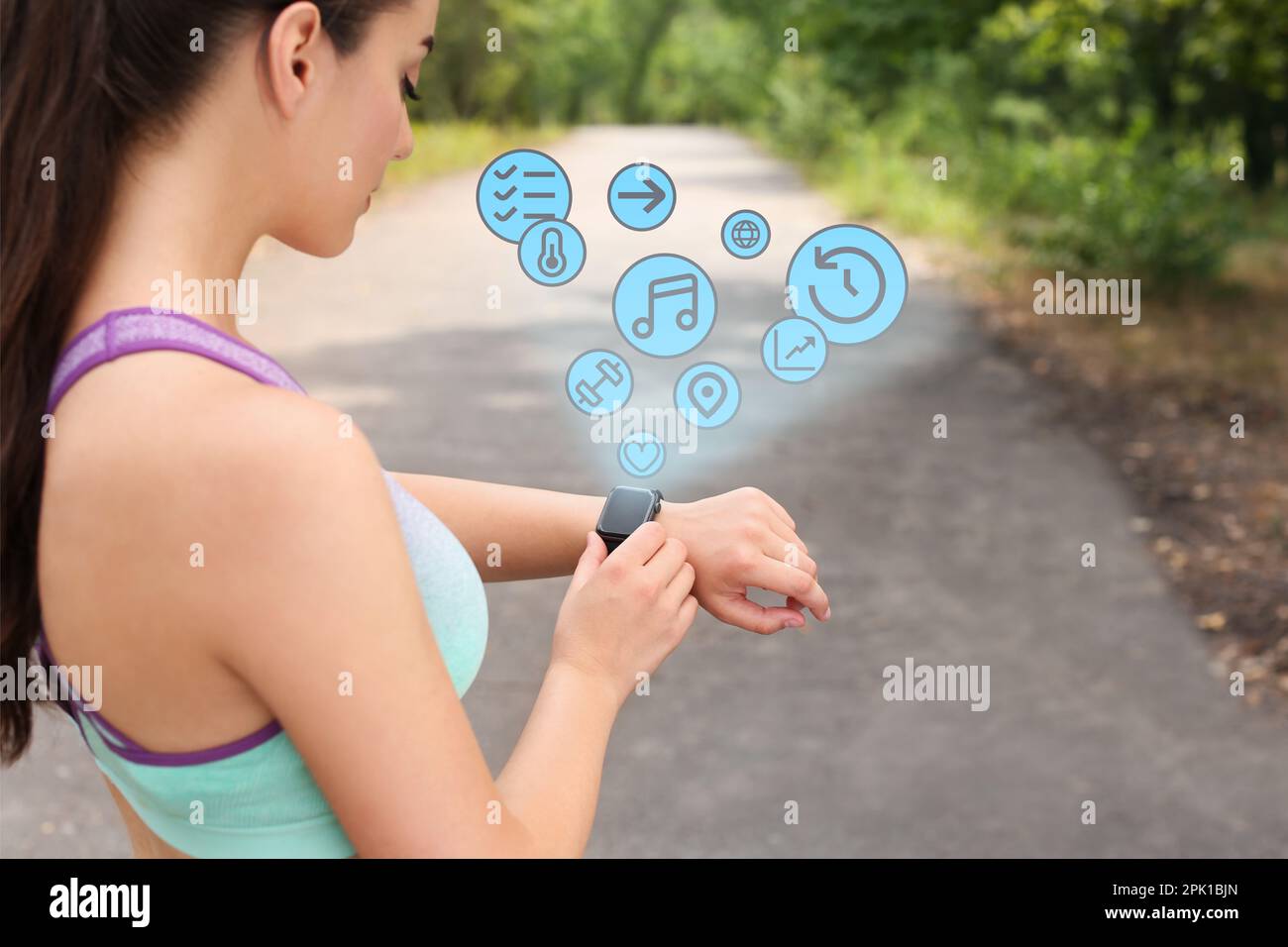 Young woman checking fitness tracker with smartwatch after training in park Stock Photo