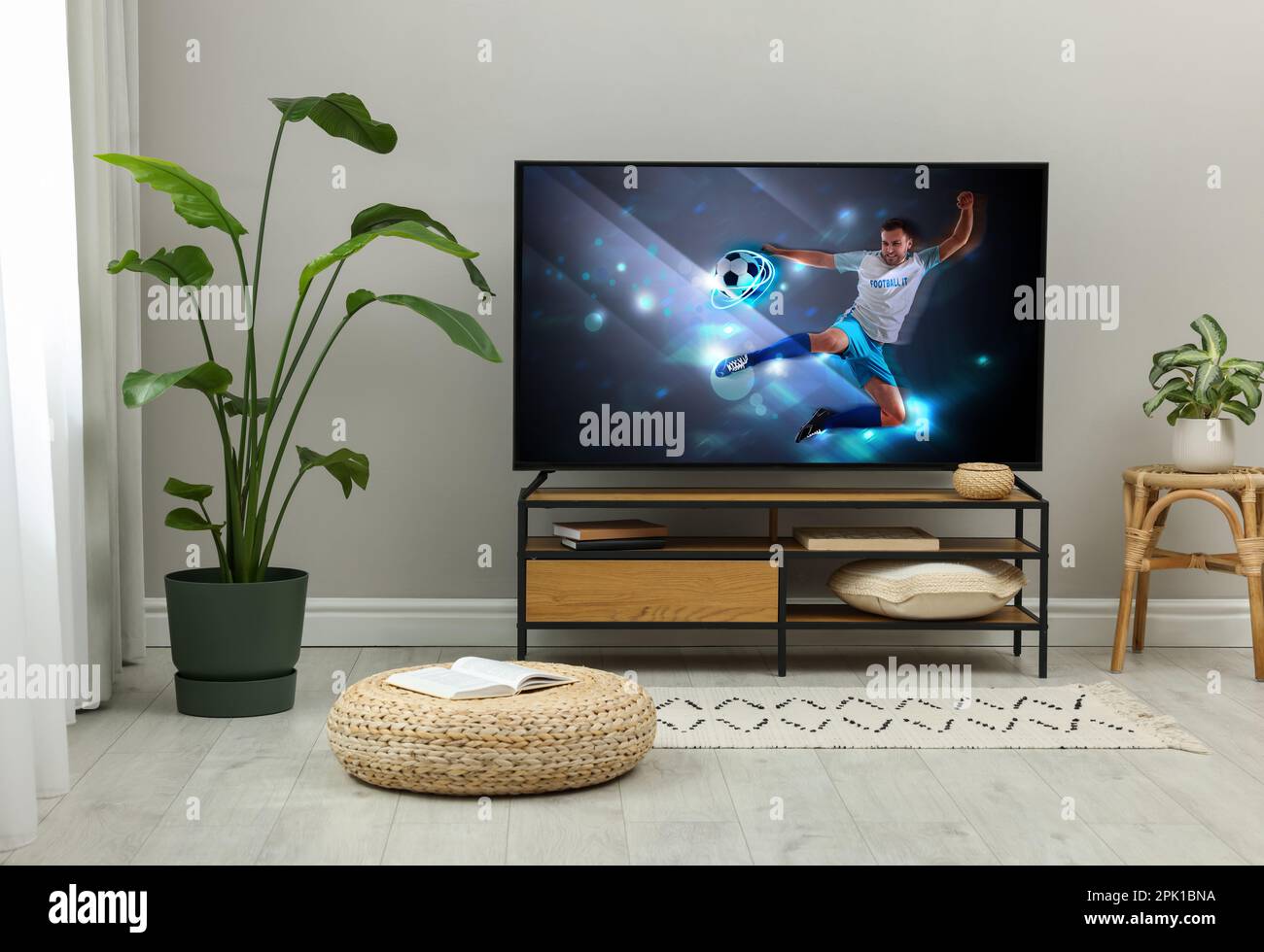 Modern TV set on wooden stand in room. Scene of football broadcasting Stock Photo