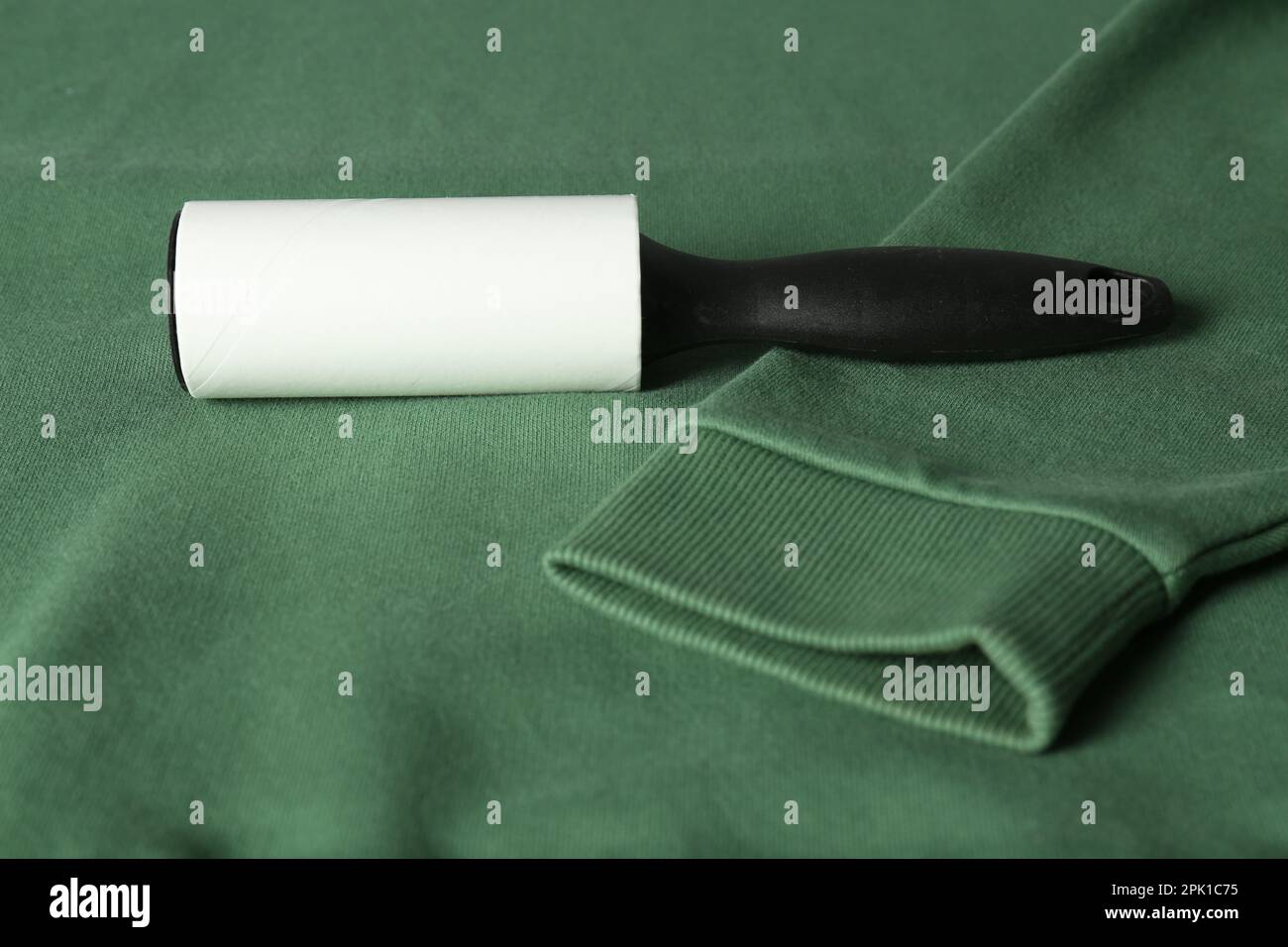 New lint roller with black handle on green sweatshirt Stock Photo