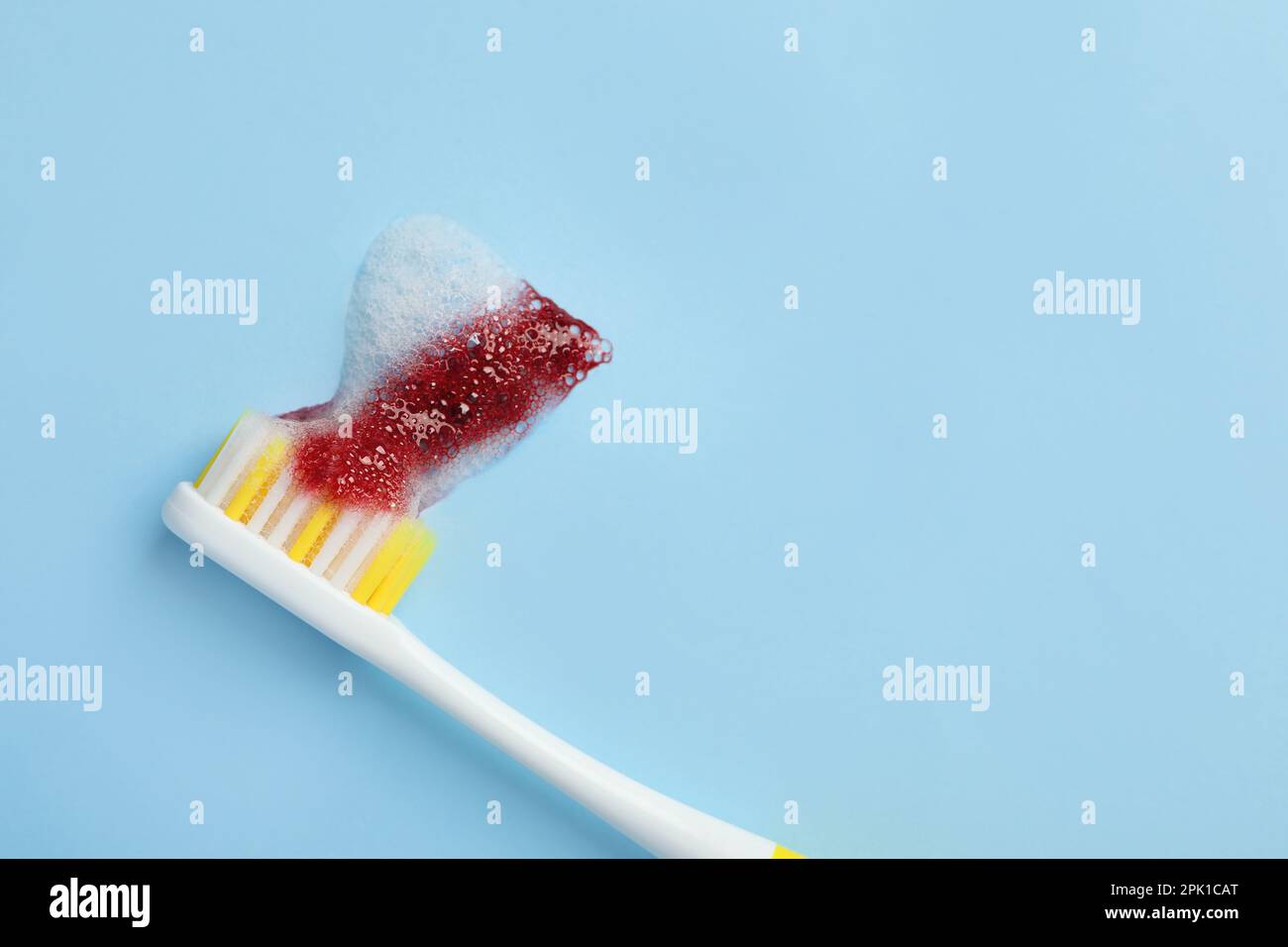Toothbrush with blood on light blue background, top view and space for