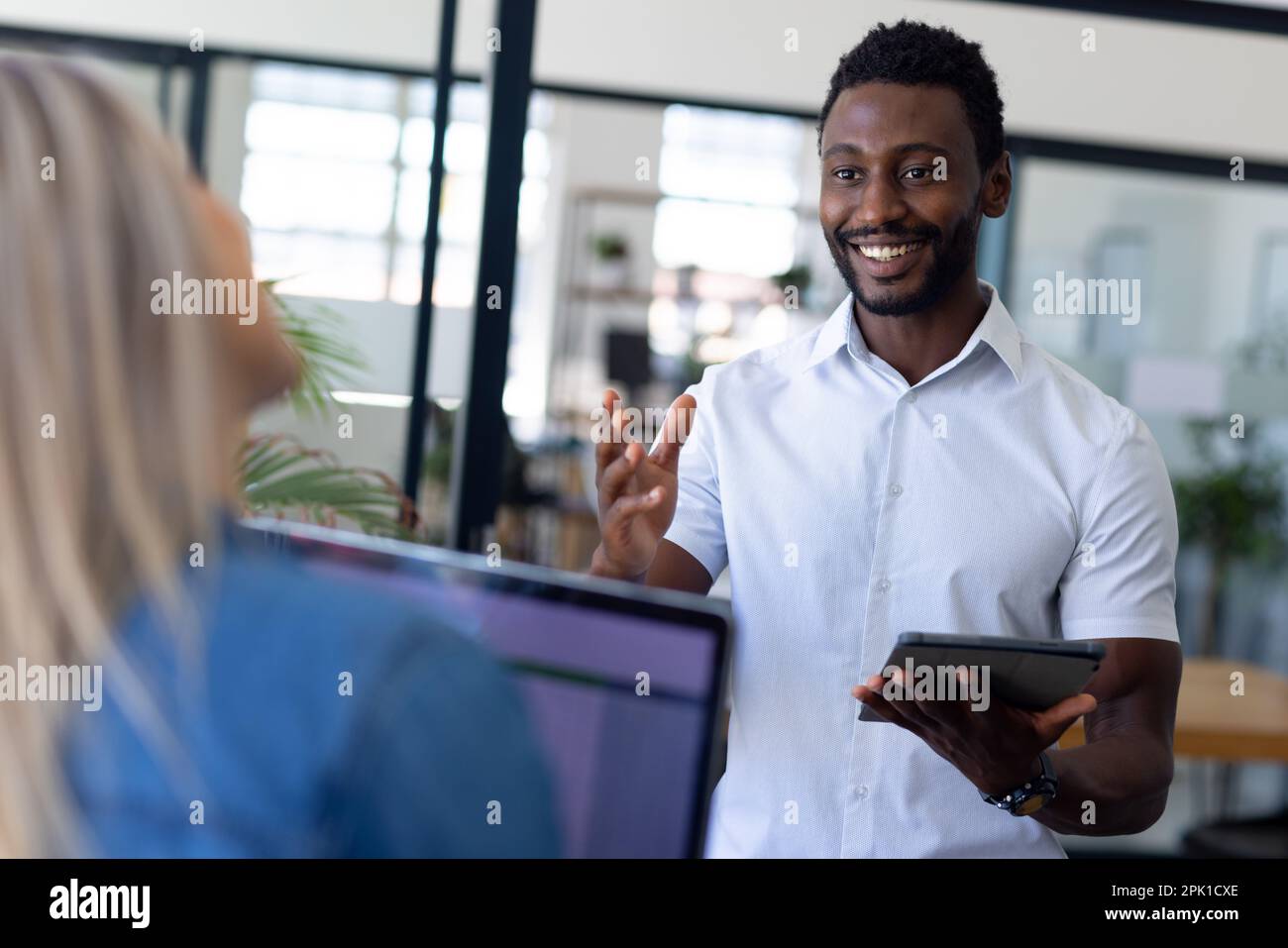 Busy diverse casual business people discussing work and using laptop in modern office Stock Photo
