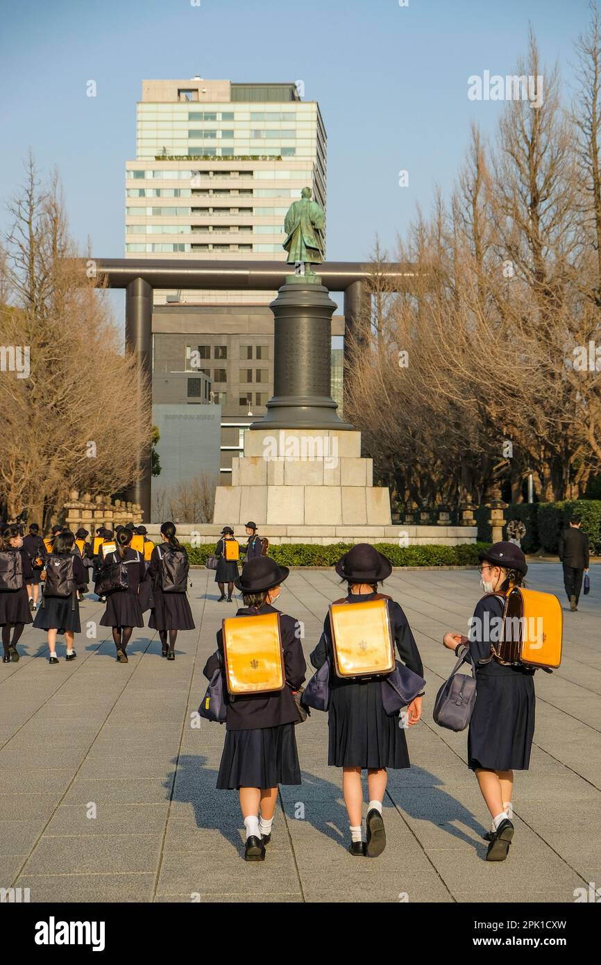 Tokyo, Japan - March 7, 2023: Girls in school uniform walking near the statue of Omura Masujiro in Chiyoda, Tokyo, Japan. Stock Photo