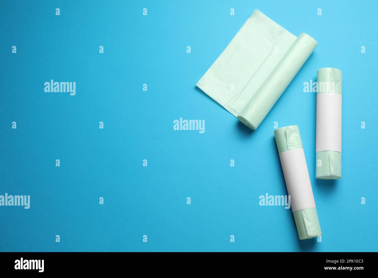 Rolls of different garbage bags on light blue background, flat lay ...