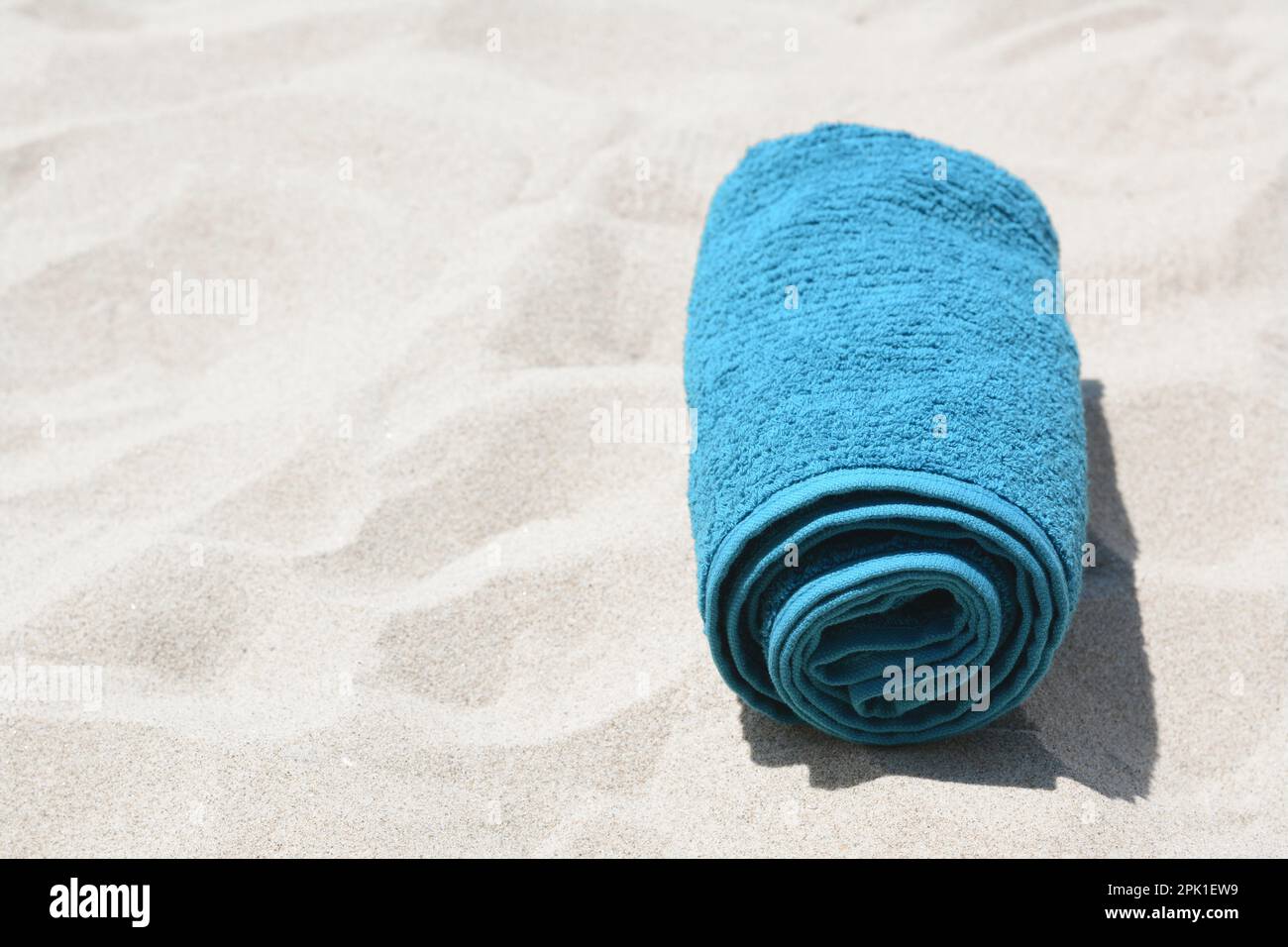 Rolled blue towel on sandy beach, space for text Stock Photo - Alamy