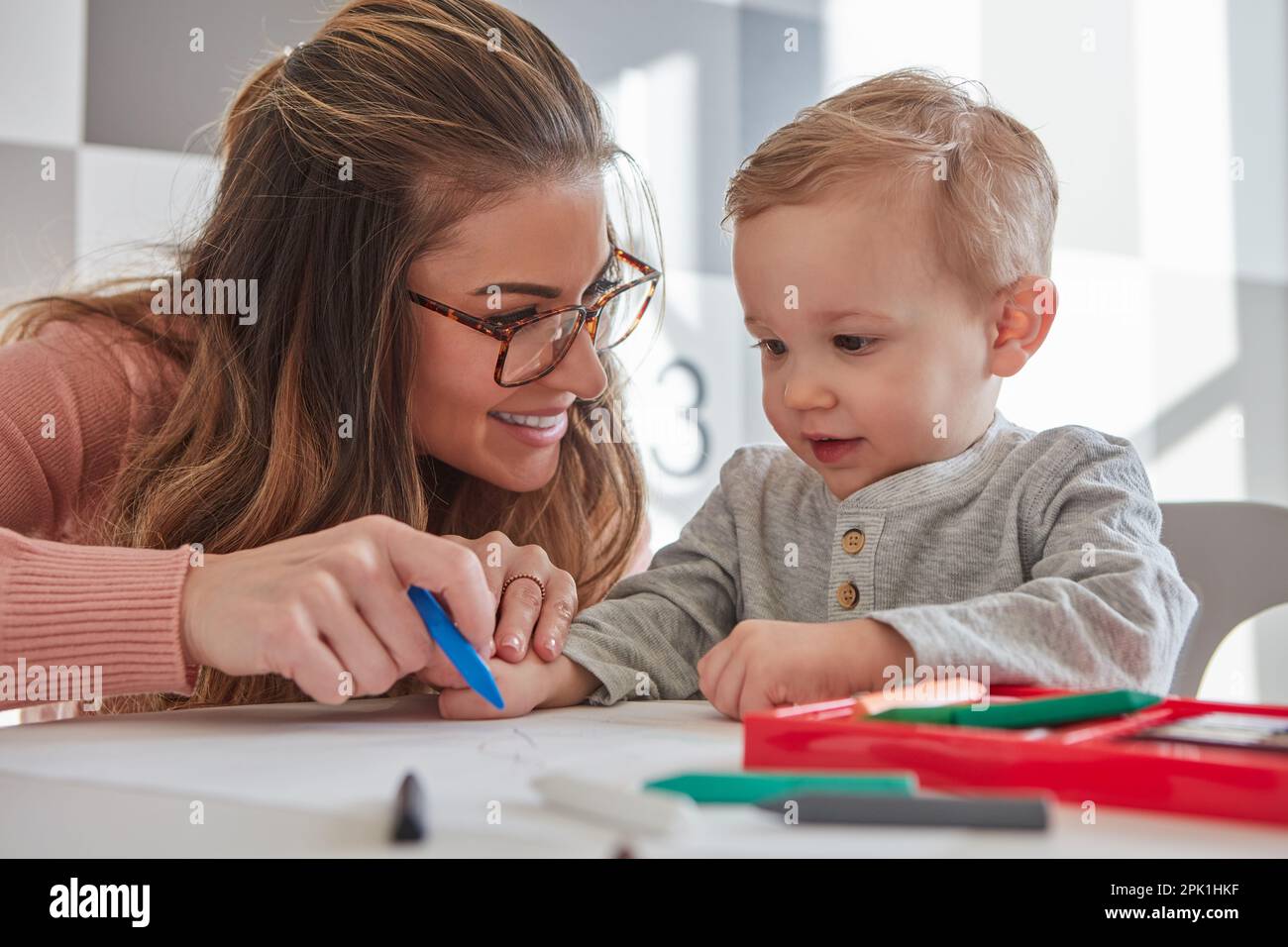 Hes only starting to learn how to hold and use crayons. a woman and her