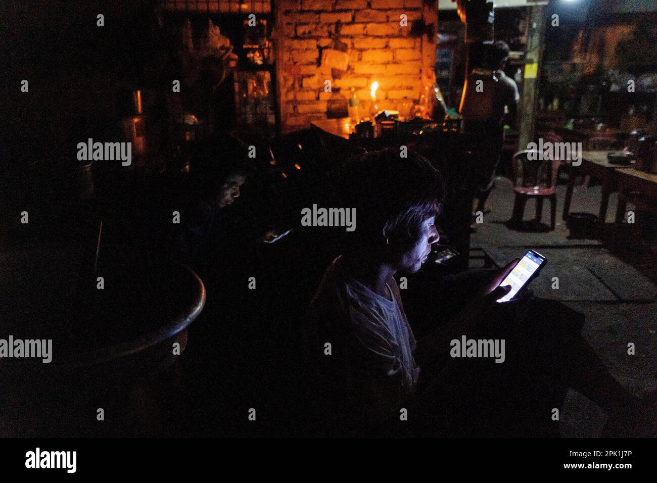 During an electricity blackout, people use cellphones and drink tea by