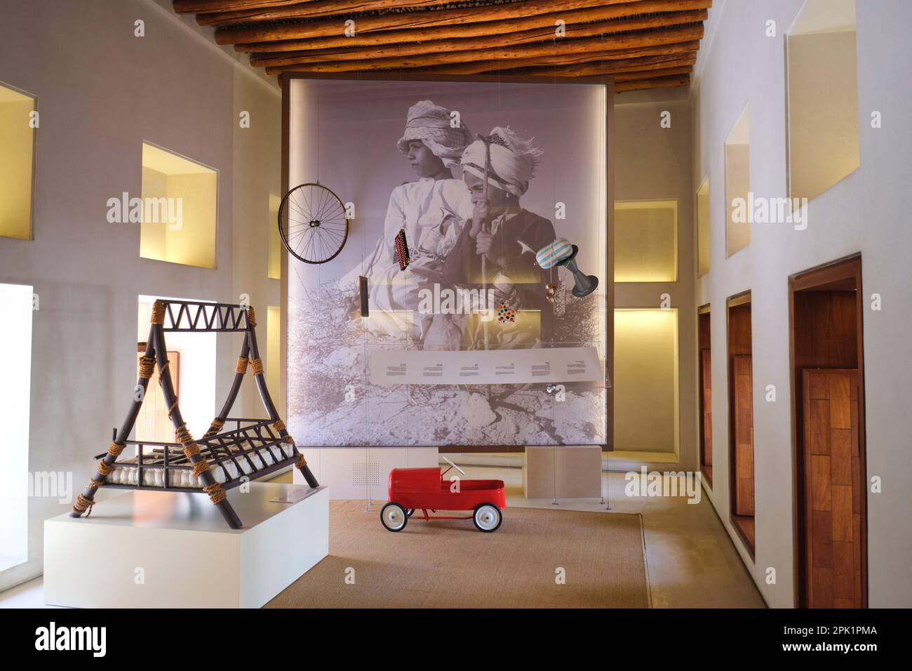 Red toy car and a traditional wood baby crib. One of the gallery