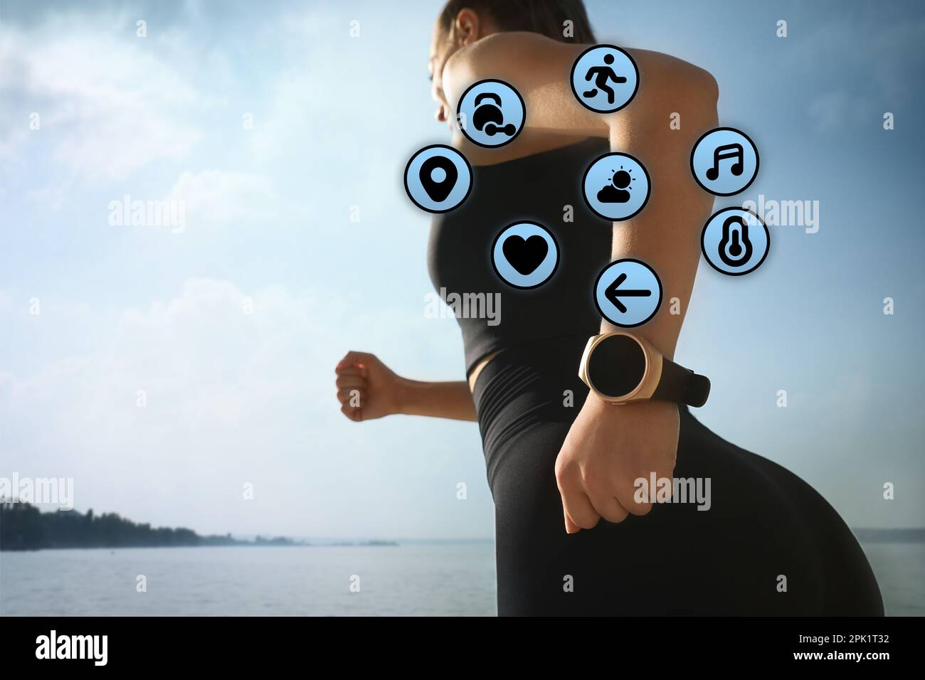 Woman wearing modern fitness tracker during training near river Stock Photo